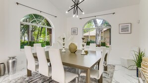 A dining area with a large table, white chairs, and a chandelier. - 8,100-sq-ft Parkland Estate w/ Luxe Outdoor Oasis! (Parkland)