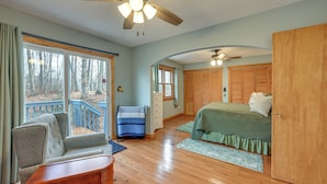 A bedroom with a wooden floor, a bed with green bedding, a wooden wardrobe, a chair, and a window with a view of trees. - Family-friendly Perks! Secluded Tuckasegee Haven (Tuckasegee)
