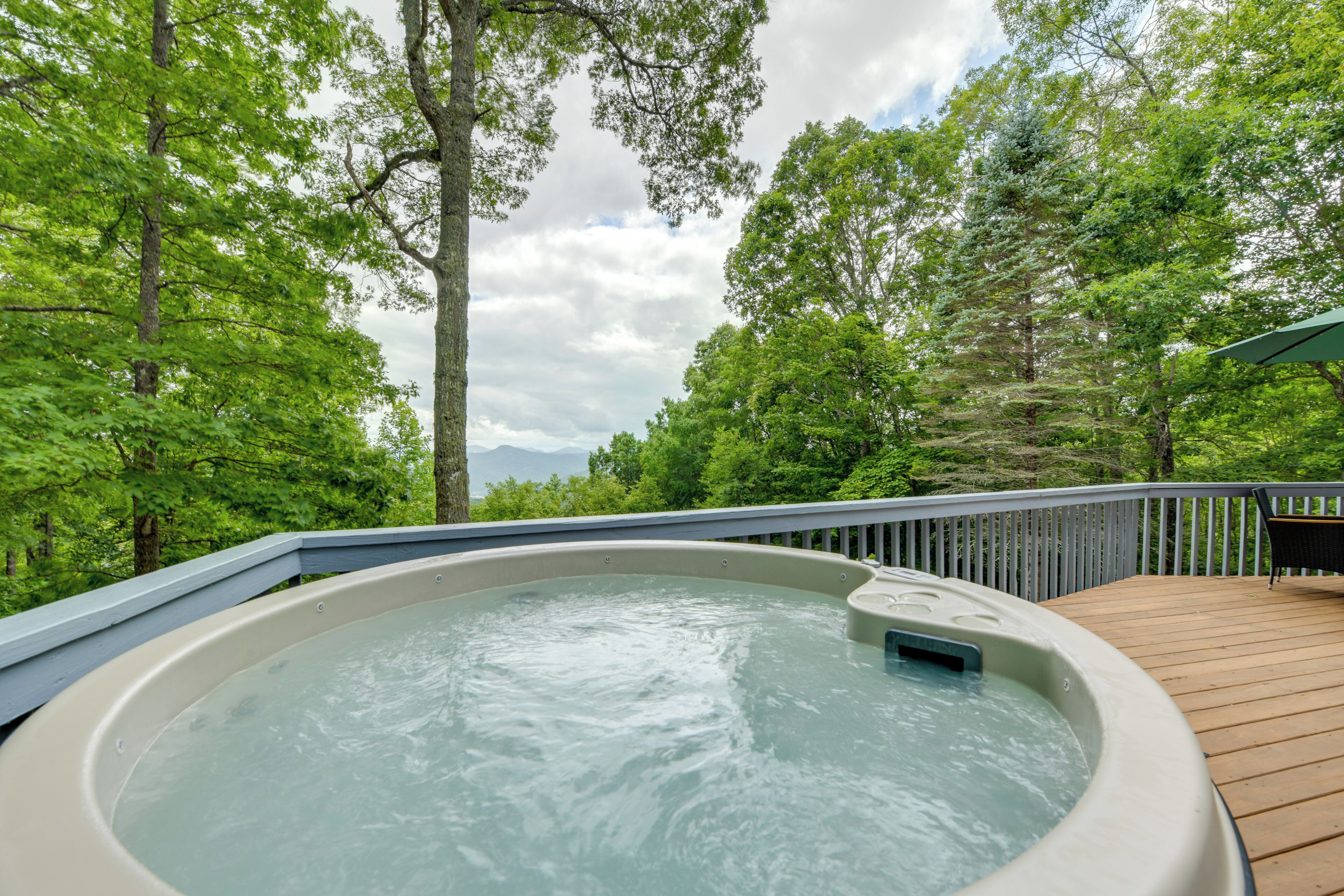 Ein Whirlpool auf einer Holzterrasse, umgeben von Bäumen.