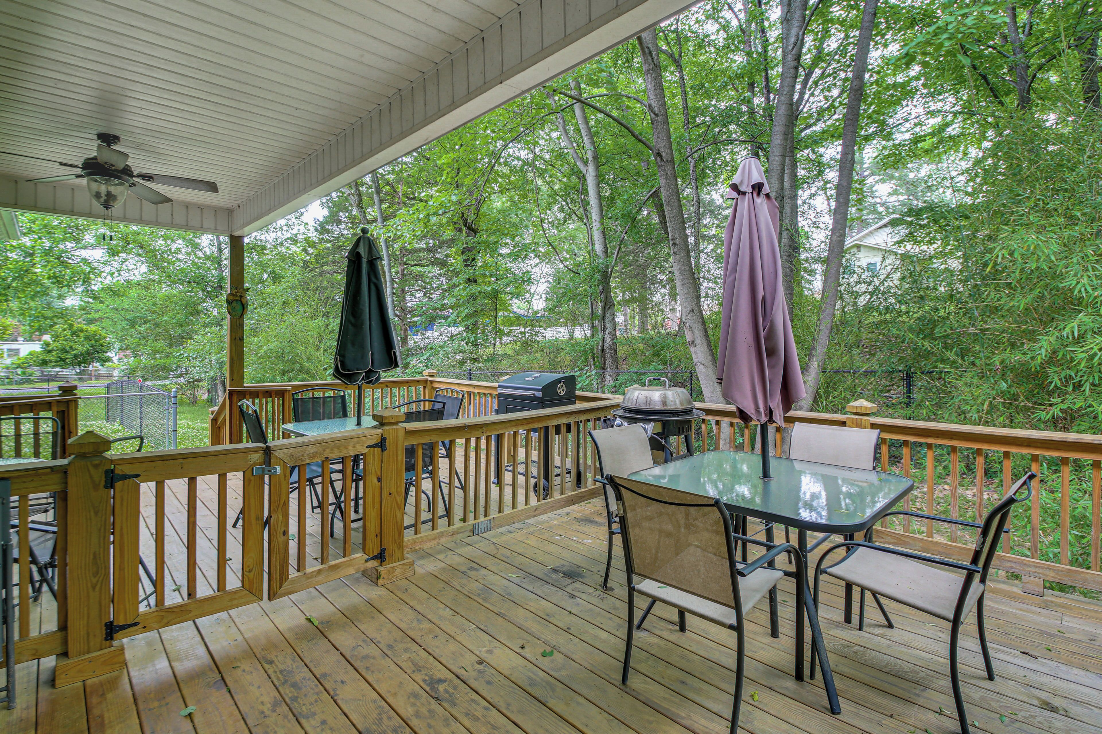 Une terrasse couverte avec une table et des chaises, un barbecue et un ventilateur de plafond.