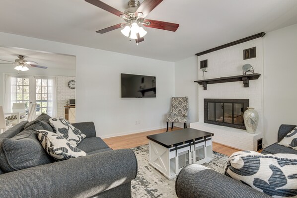 A modern living room with a fireplace, grey sofas, a coffee table, and a ceiling fan.