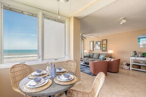 Ein Essbereich mit Meerblick, ein Wohnzimmer mit Sofa und Couchtisch sowie ein Deckenventilator.