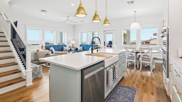 A spacious kitchen with a central island, white cabinetry, and a dining area with a round table and chairs. - Coastal Breeze Cottage near beach water views (Port O'Connor)