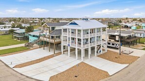 A multi-story building with a balcony, a covered area, and a dock. - Coastal Breeze Cottage near beach water views (Port O'Connor)