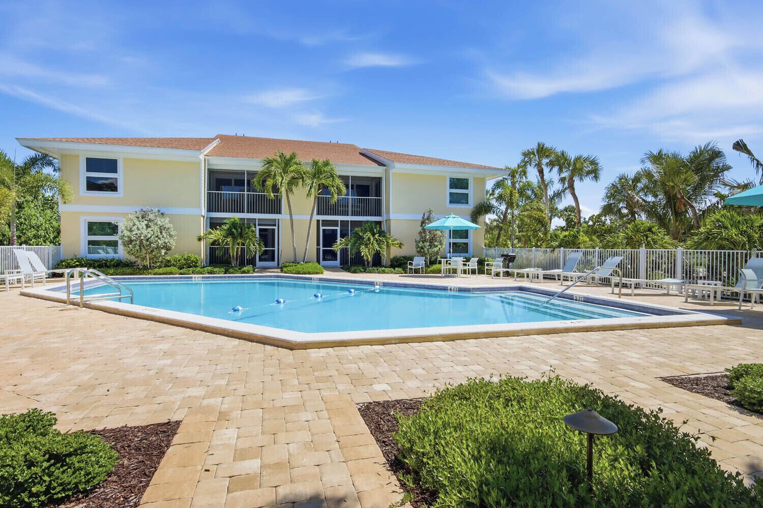 Un hôtel doté d’une piscine, d’un espace extérieur aménagé et de palmiers.