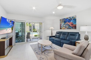 Una sala de estar moderna con televisión, sofá, mesa de centro y un cuadro.
