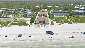 Ein Küstenhotel mit mehreren Gebäuden, ein Strand mit Sonnenschirmen und freier Meeresblick.