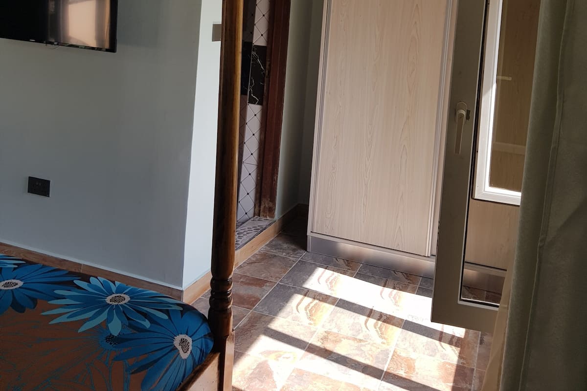 A room with a bed, a wardrobe, a door, and a television on the wall.