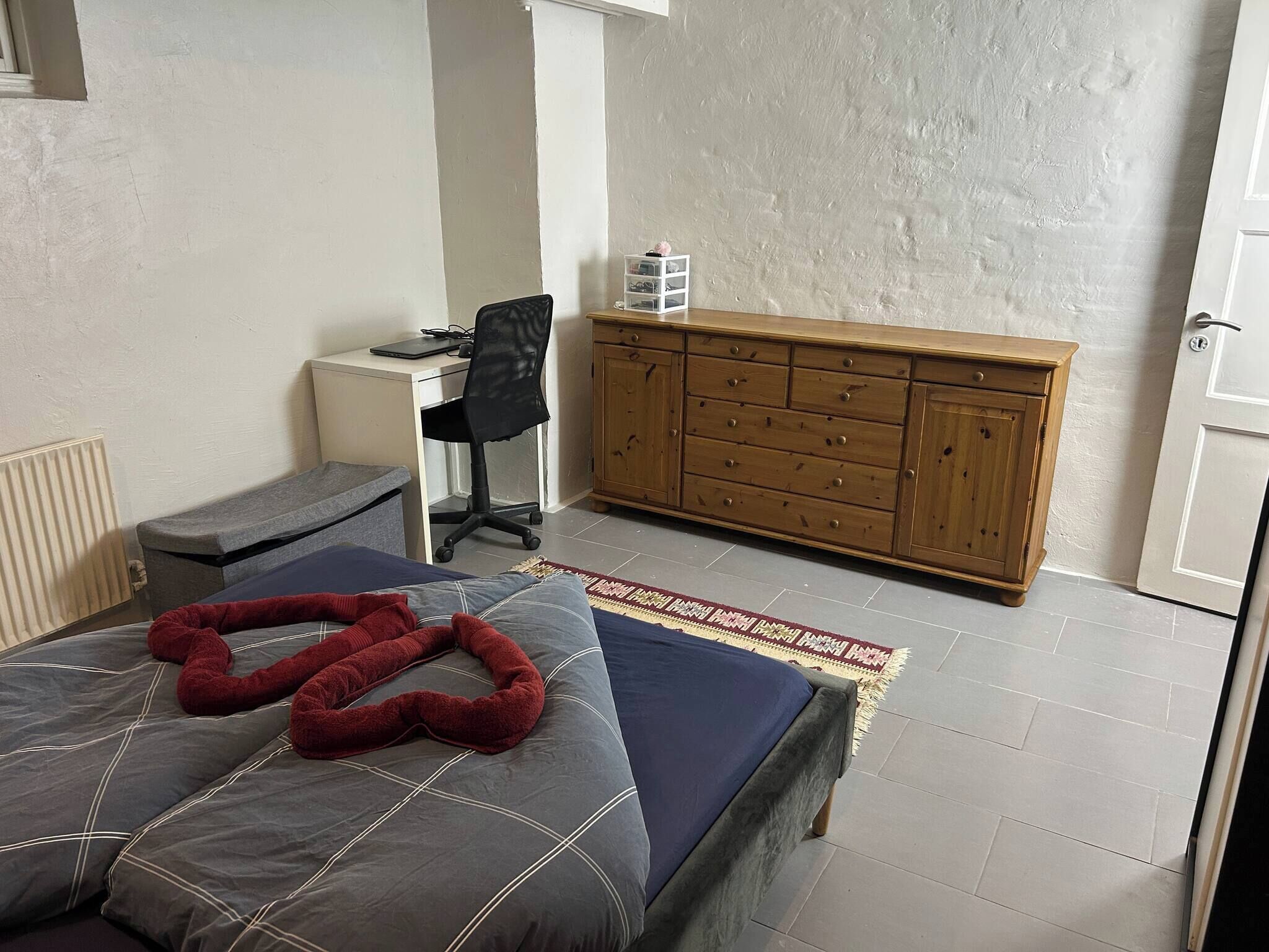 Ein Schlafzimmer mit einem Bett, einem Schreibtisch, einem Stuhl und einem Holzschrank.