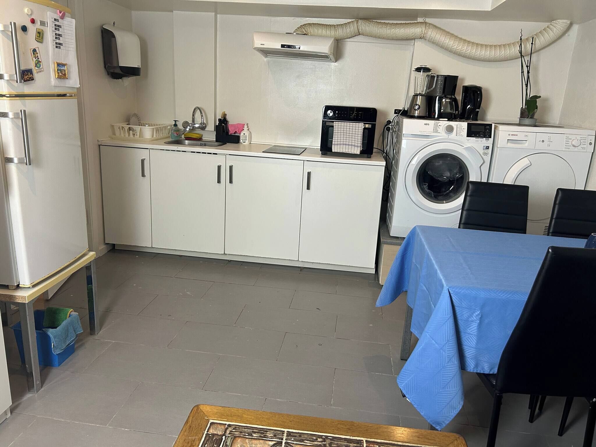 A compact kitchen with a refrigerator, sink, and washing machine.