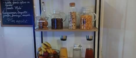 Un buffet de petit-déjeuner proposant une variété d’aliments et de boissons, notamment un panier de fruits, une carafe de jus d’orange et un assortiment de condiments.