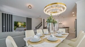 Un comedor moderno con una mesa de mármol, sillas blancas y una lámpara de araña.