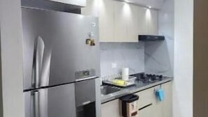 Una cucina compatta con frigorifero in acciaio inossidabile, piano cottura a gas e mobili bianchi.