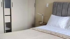 Una camera da letto con un letto, un comodino, una lampada, un armadio e una cabina armadio.