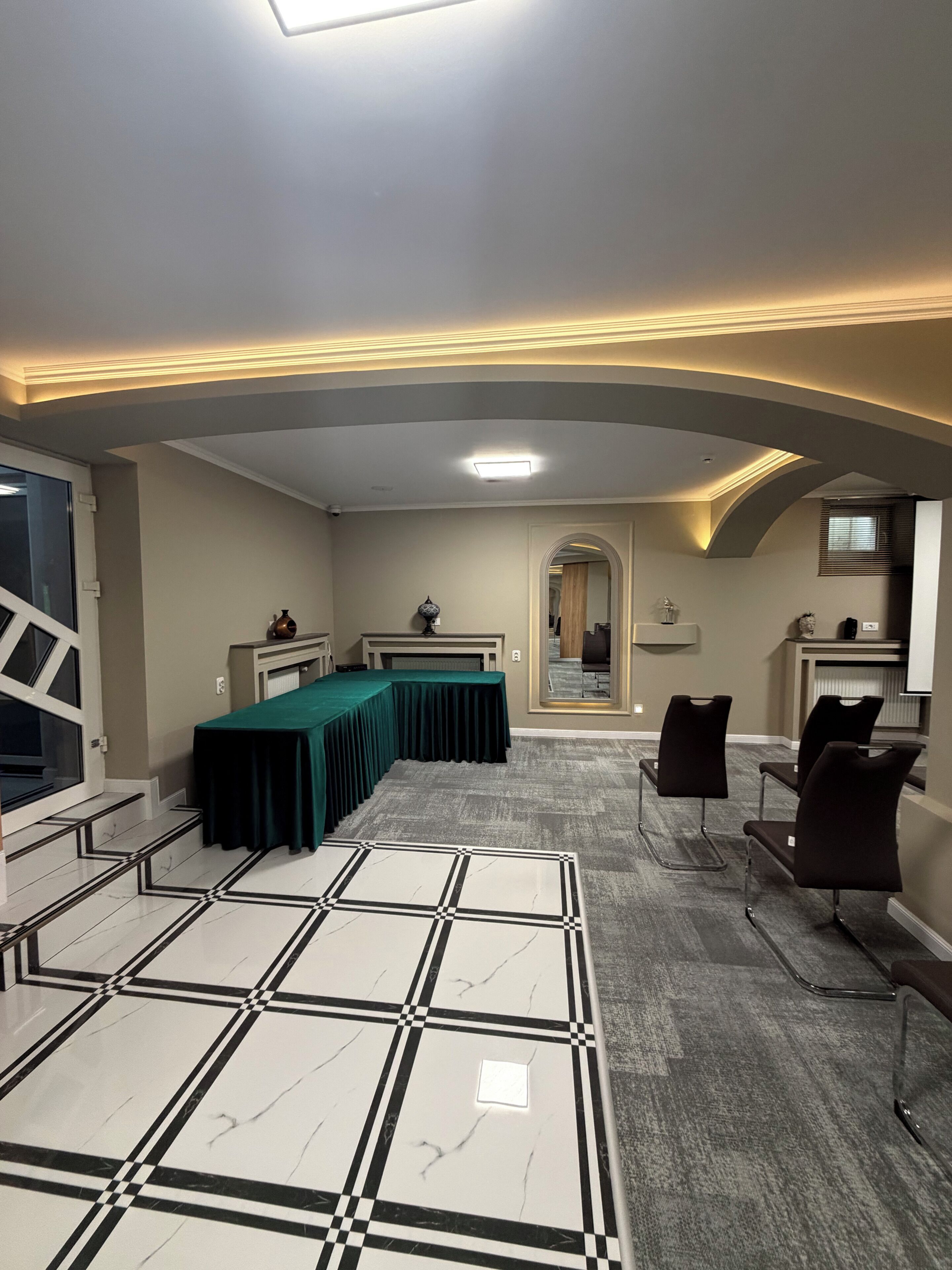Una sala de conferencias con una mesa larga, sillas y piso estampado.