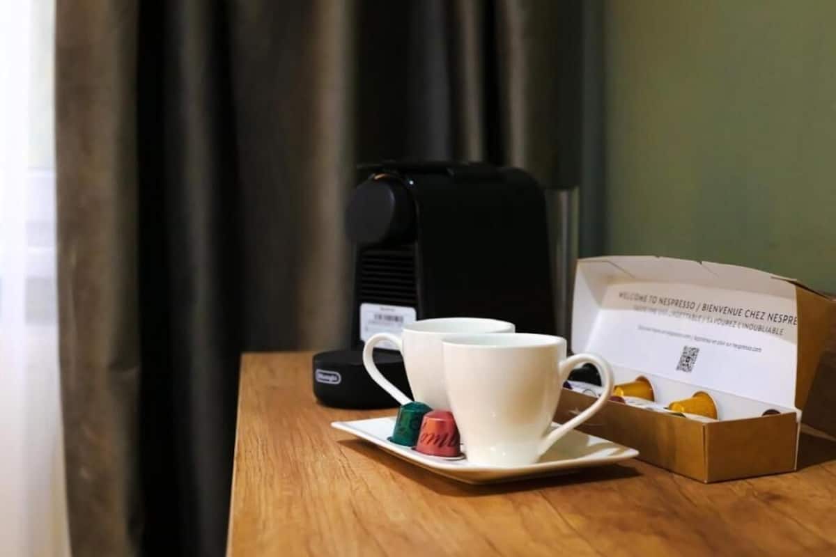 Una preparación de café con una taza, una caja de biscotti y una cafetera sobre una mesa.