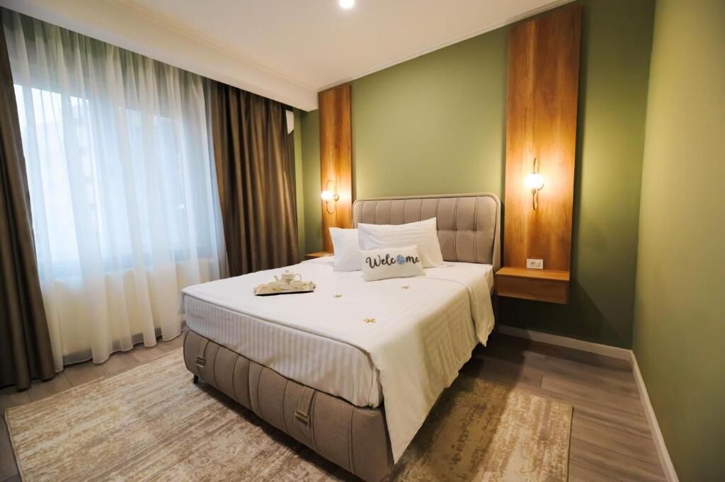 Ein Schlafzimmer mit Bett, Vorhängen, Wandleuchten und einem Nachttisch.