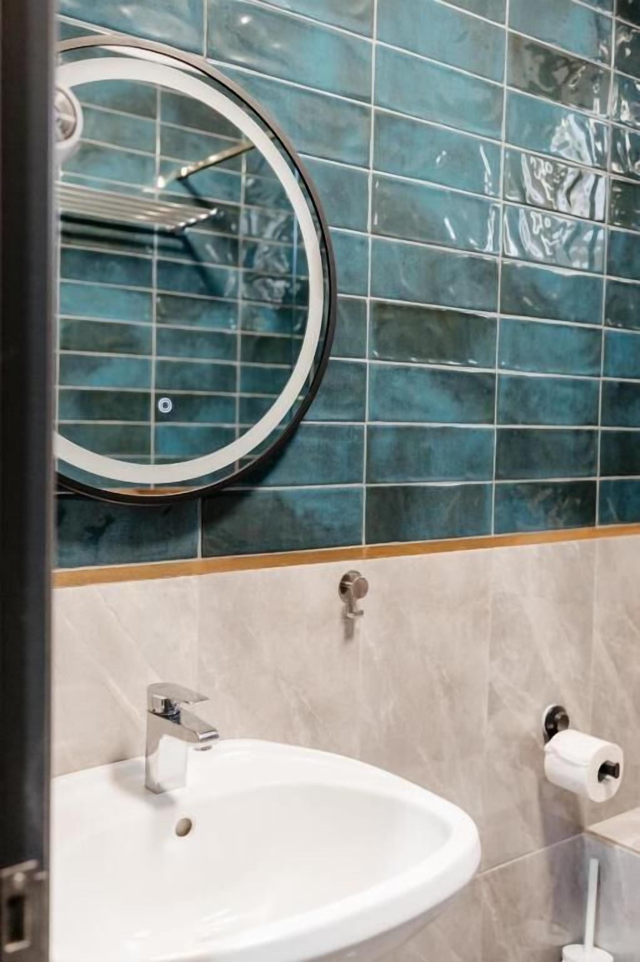 Een badkamer met een wastafel, spiegel en wc-papierhouder.