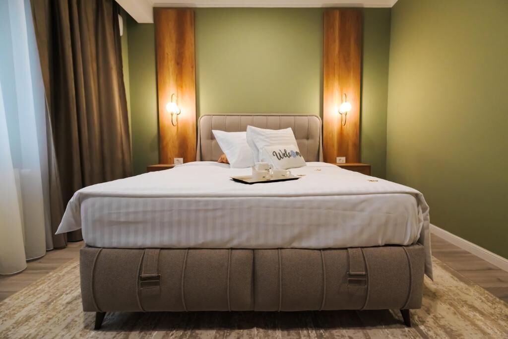 A neatly made bed with pillows, a tray with a cup and saucer, and two wall-mounted lamps.