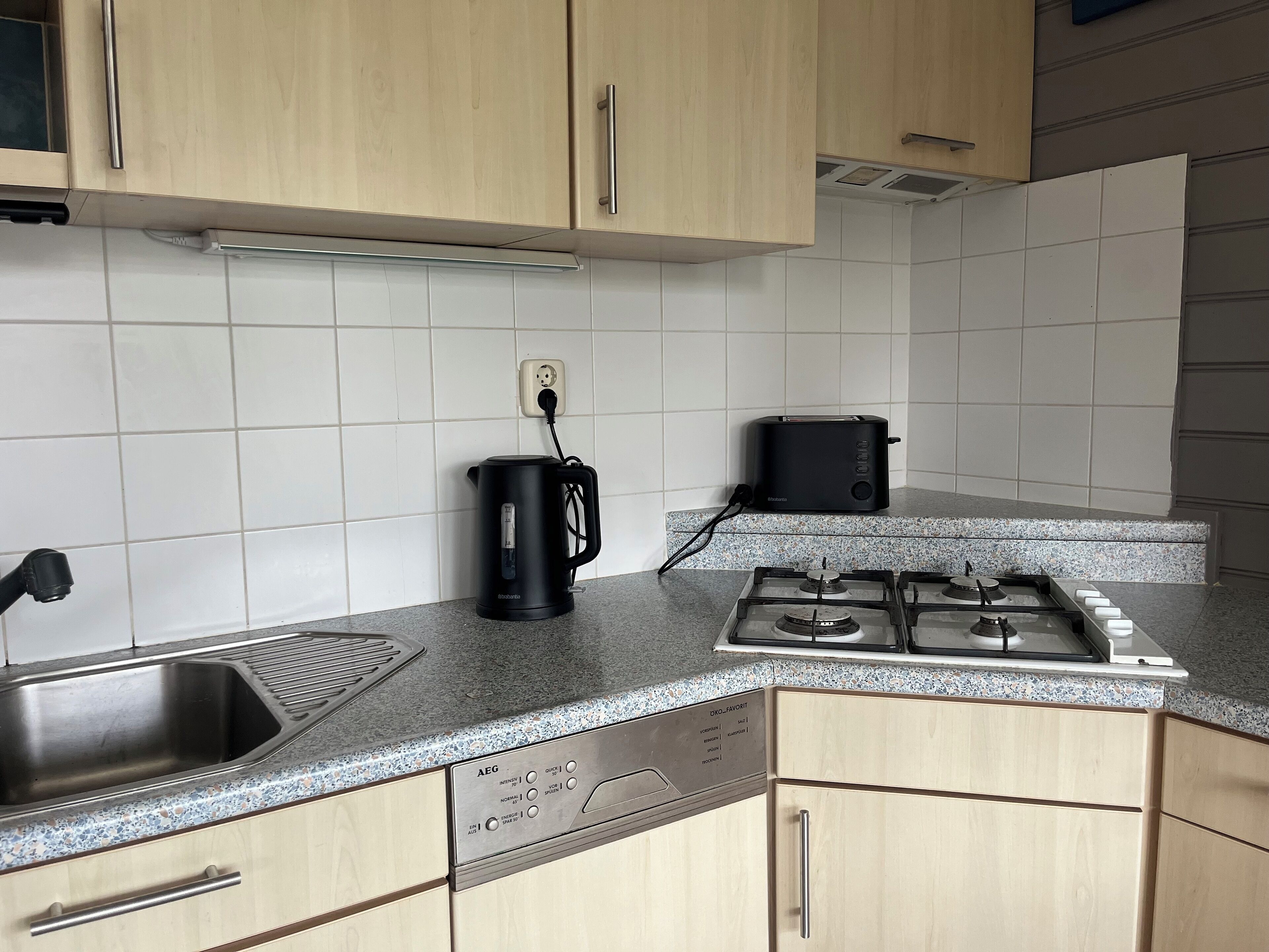 A kitchen with a stainless steel sink, a black coffee maker, a toaster, and a gas stove.