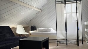 A high-ceilinged room with a bed, a black coffee table, a white chair, and a large window with curtains. - For rent Island Happiness! (Oudesluis)