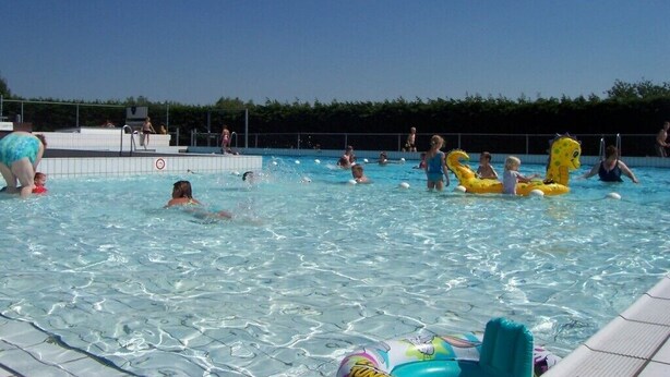 A swimming pool with people and inflatable toys. - For rent Island Happiness! (Oudesluis)