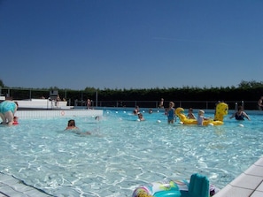 A swimming pool with people and inflatable toys.