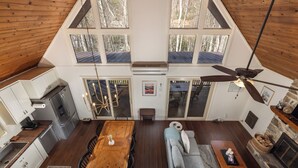 A spacious loft with a high ceiling, a dining area, a sofa, a fireplace, and a kitchen with a refrigerator and cabinets. - Smore than enough! Powder Horn Mountain - 3K,2 twin bunks, Pets OK,Pool table (Deep Gap)