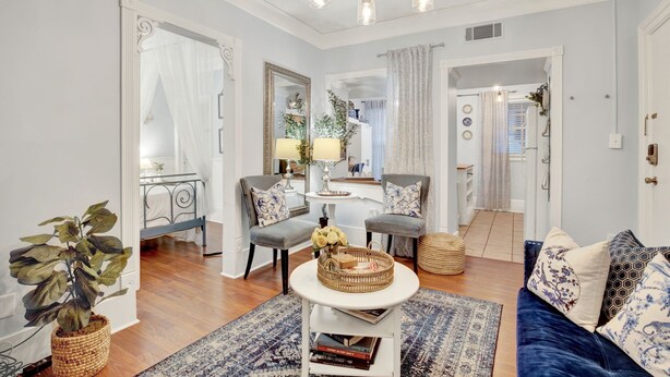 A living room with a chandelier, two armchairs, a sofa, a coffee table, and a potted plant. - Charming Downtown Apartment (Savannah)