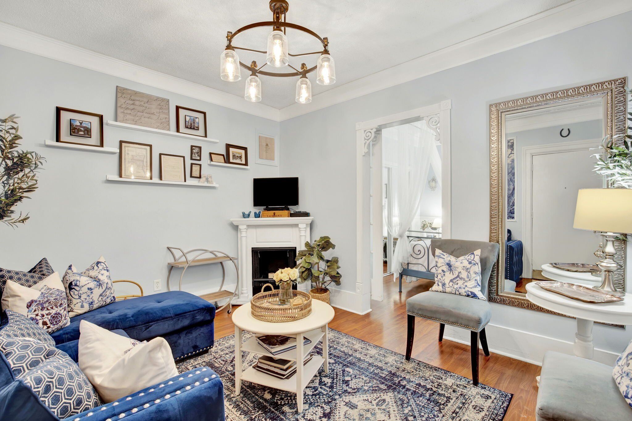 Een woonkamer met een open haard, blauw meubilair, een televisie en decoraties aan de muur.