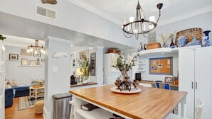 A modern kitchen with a wooden island, white cabinetry, and decorative items. - Charming Downtown Apartment (Savannah)