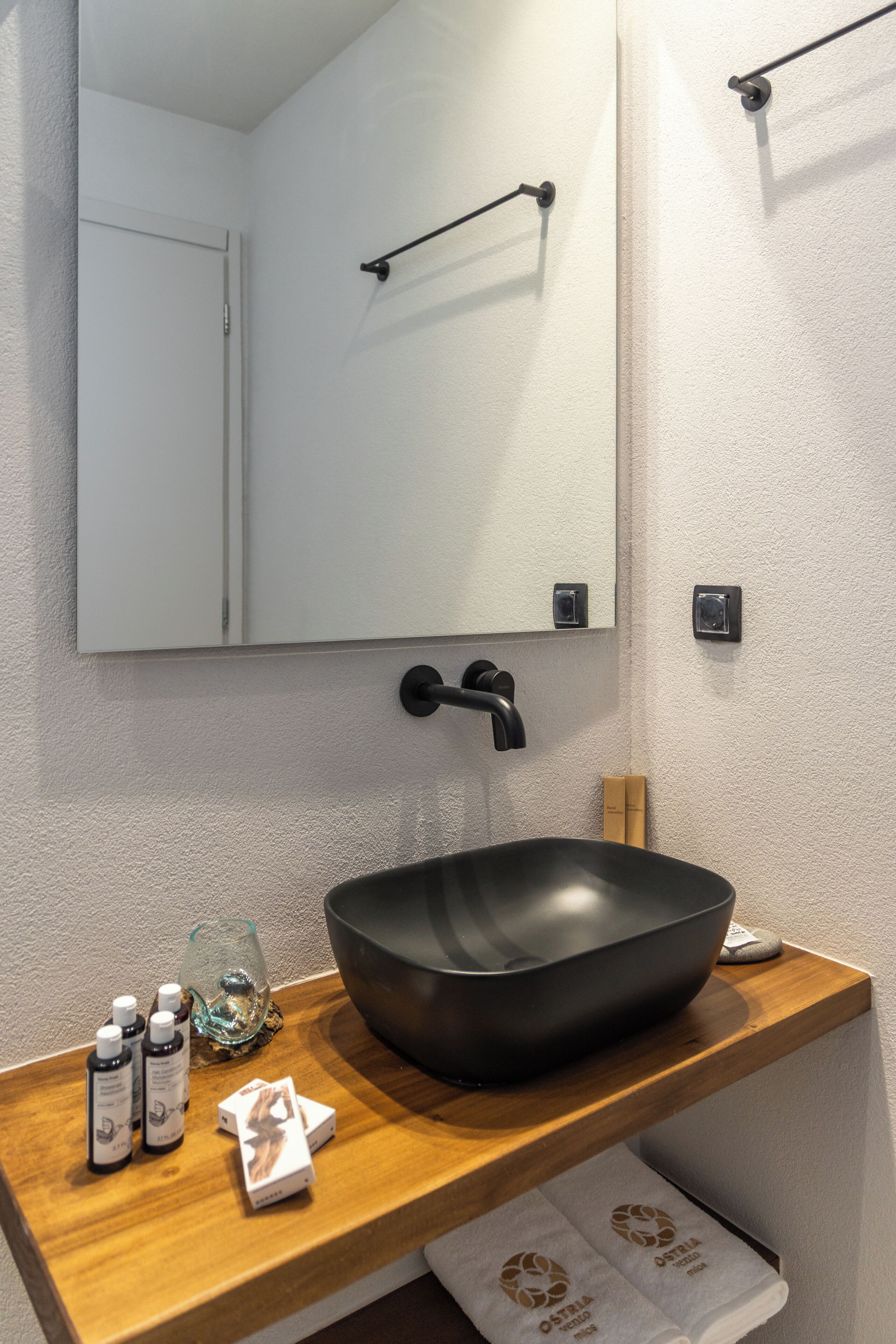 Un baño con un lavabo negro, encimera de madera y un espejo encima.