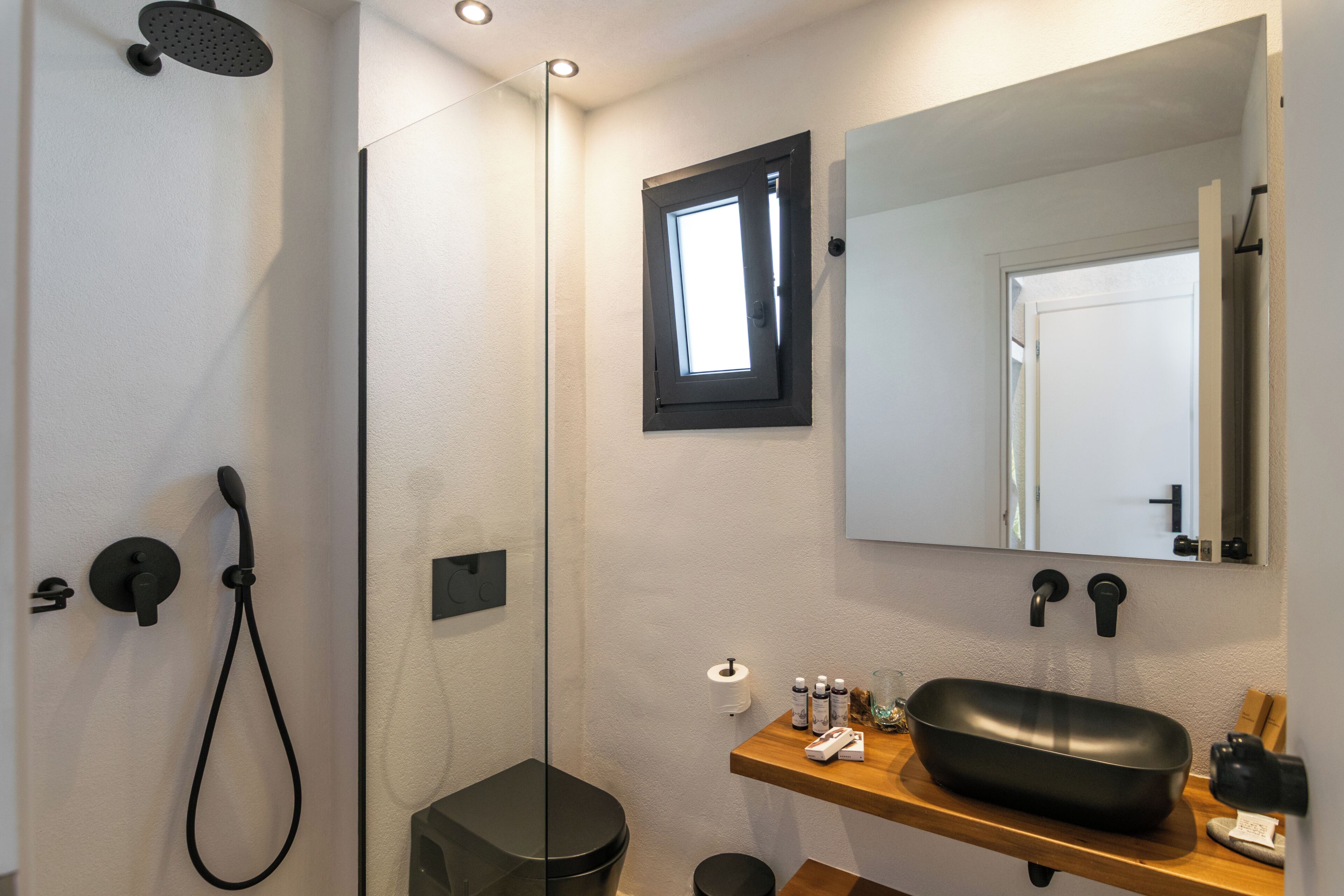 A bathroom with a shower, toilet, sink, and mirror.