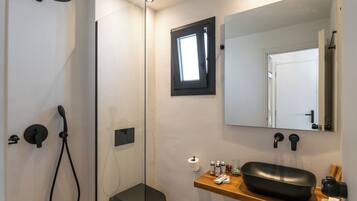 A bathroom with a shower, toilet, sink, and mirror.