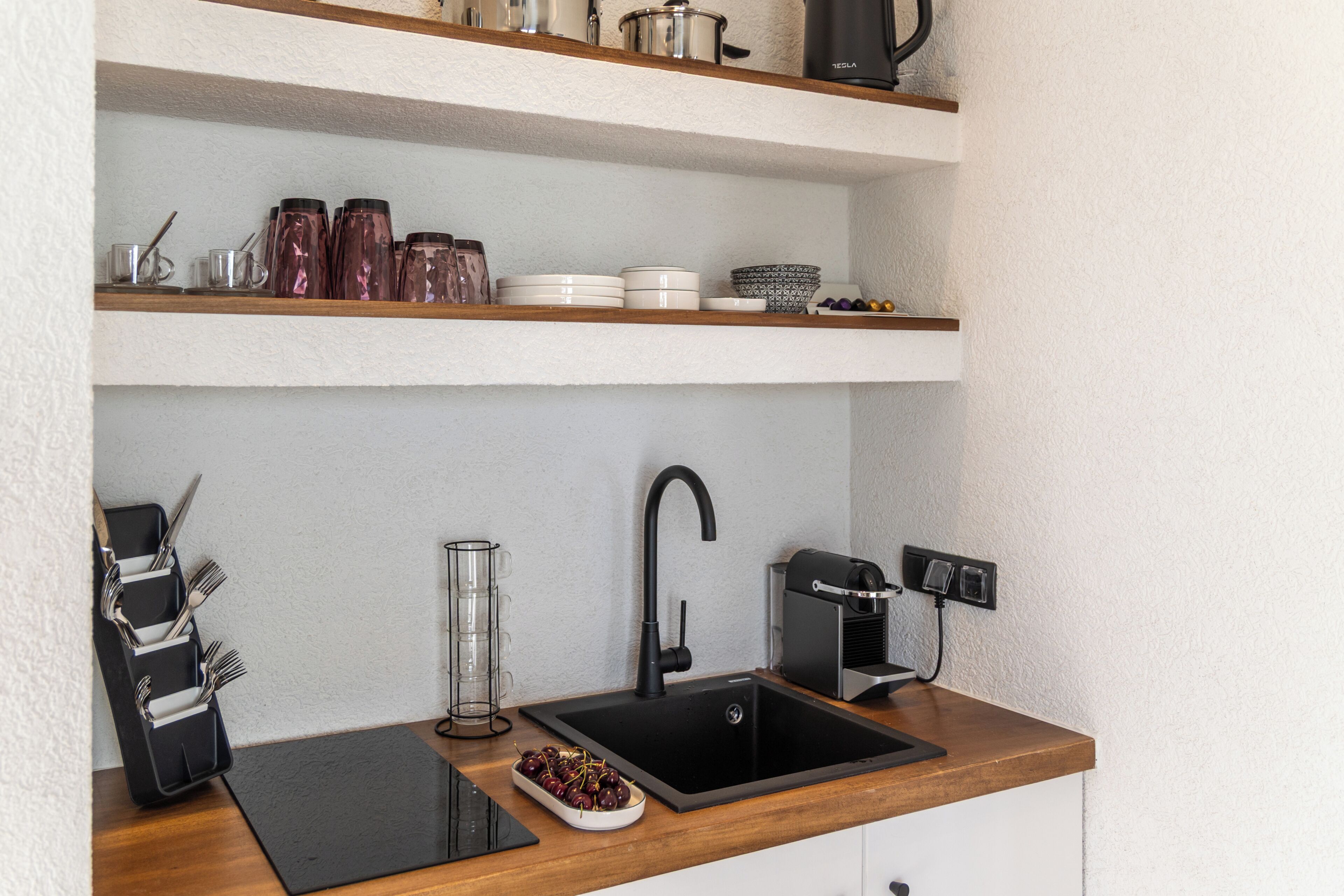Une cuisine moderne avec un évier noir, un plan de travail en bois et des appareils électroménagers en acier inoxydable.