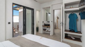 Un dormitorio moderno con cama, vestidor y baño con lavamanos y espejo.