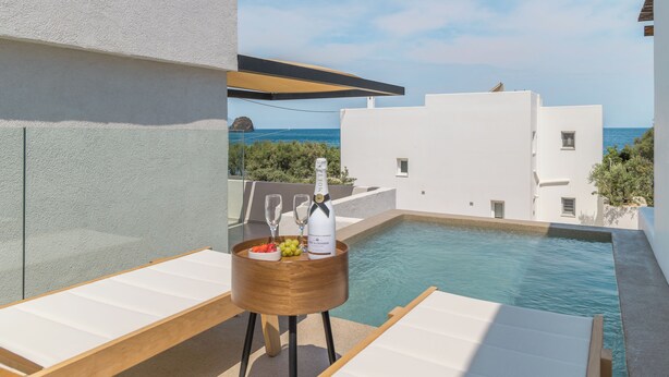 Un área junto a la piscina con una mesa de madera, una botella de champán y copas.