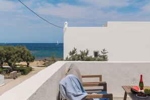 Ein Balkon mit Meerblick, ein weißes Gebäude und ein Tisch mit Flasche und Obst.
