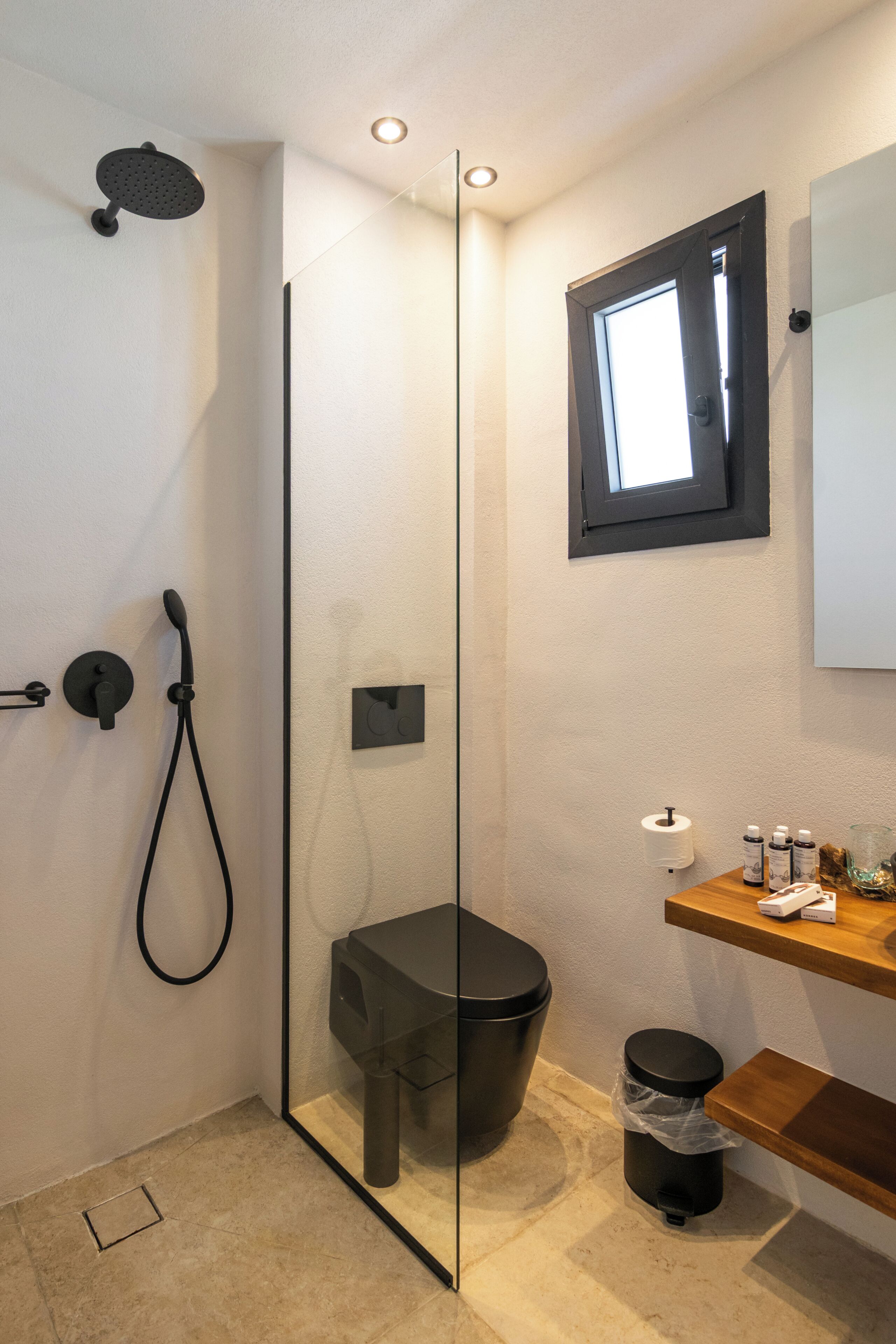Un baño moderno con cabina de ducha de vidrio, inodoro, bidé, lavamanos y ventana.