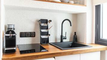 Een moderne keuken met een zwarte spoelbak, een koffieapparaat en een ingebouwd oplaadstation.