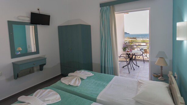 A hotel room with two beds, a TV, a wardrobe, and a balcony with outdoor seating. - Armonia Apartments (Chania)