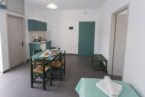 Une cuisine compacte avec des meubles de couleur turquoise, une table à manger avec des chaises et un banc avec une serviette.