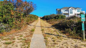 Een pad dat naar een strand leidt, met een bord waarop '180 A Ocean Blvd Beach Access' staat.