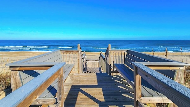 A wooden boardwalk leading to the beach with benches and railings. - Captain's R&R - 5 BR Oceanfront Home w/Private Pool & Hot Tub - Dogs Allowed (Southern Shores)