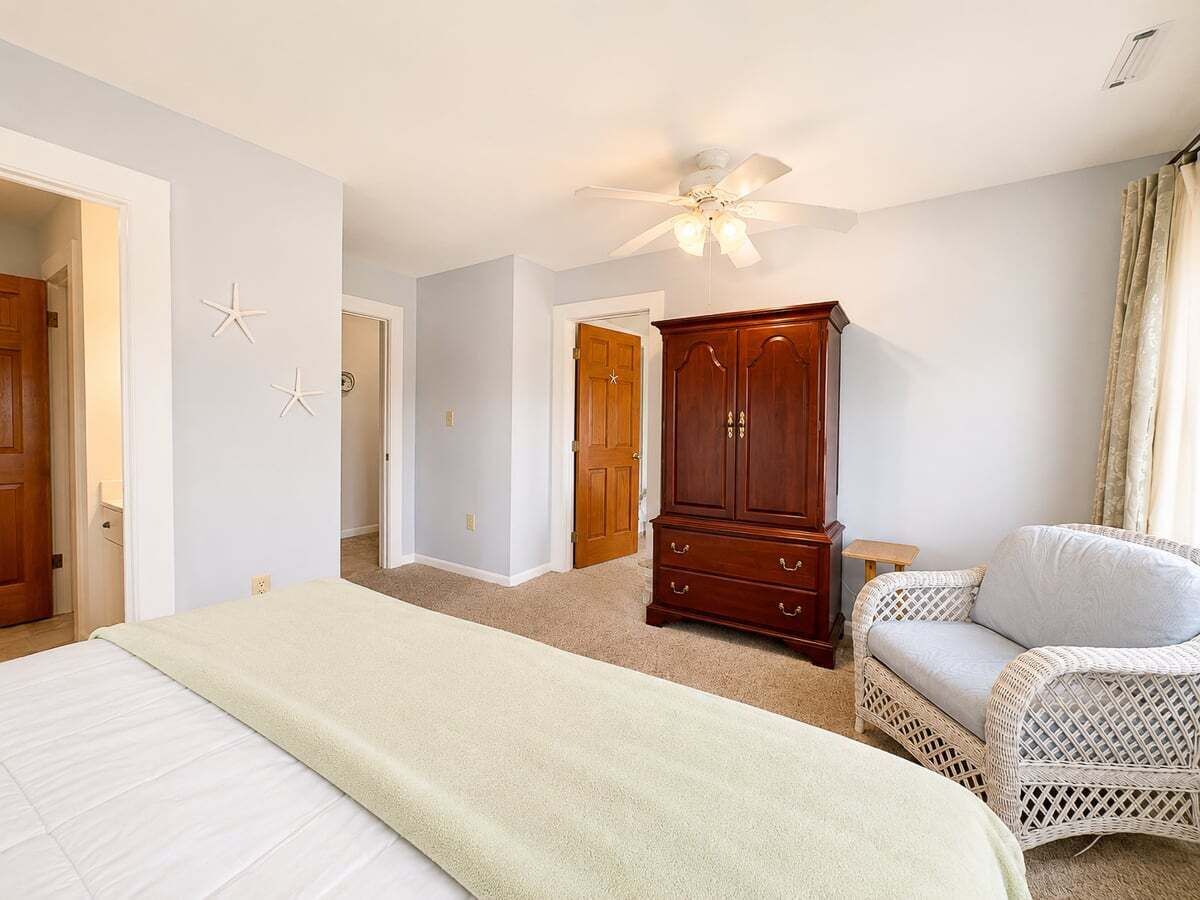 Une chambre à coucher avec un lit, une armoire, une chaise et un ventilateur de plafond.