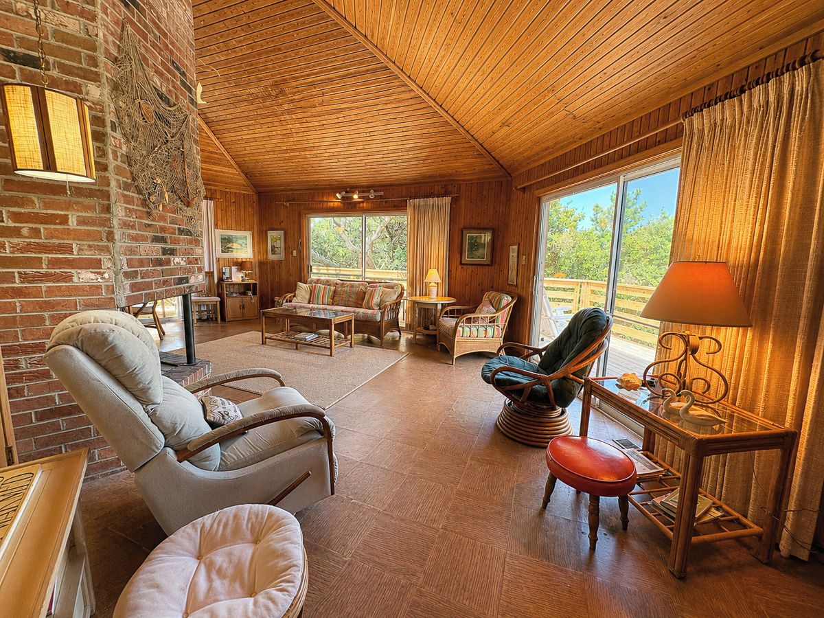 Une pièce chaleureuse avec une cheminée, des meubles en bois et une grande fenêtre.