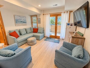 Ein Wohnzimmer mit einem Ecksofa, zwei Sesseln, einem Couchtisch und einem Fernseher.