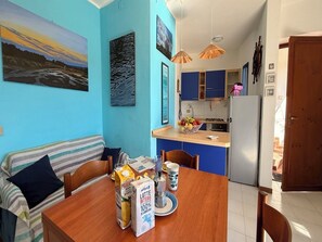 Un comedor acogedor con una mesa de madera, sillas y una pared azul decorada con obras de arte.