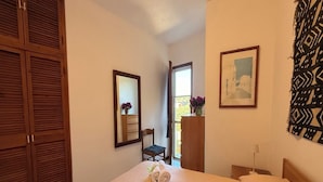 Ein Schlafzimmer mit Bett, Holzschrank, Spiegel, Stuhl, Schreibtisch und Fenster.
