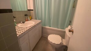 A bathroom with a sink, mirror, toiletries, a bathtub, and a toilet. - Room-vermaurel Sweet Lodge (Bathurst)